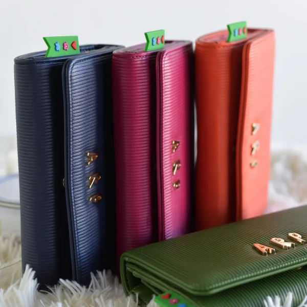 Este billetero con tapa combina elegancia y funcionalidad en un formato compacto y práctico. Confeccionado en piel vegana grabada en líneas verticales, ofrece un diseño sobrio pero con el toque distintivo de Agatha Ruiz de la Prada gracias a los detalles metálicos dorados. En su interior encontrarás un bolsillo con cremallera que garantiza la seguridad de monedas o pequeños objetos, además de espacio para billetes y tarjetas, manteniendo todo perfectamente organizado. Medidas: 19*17*8