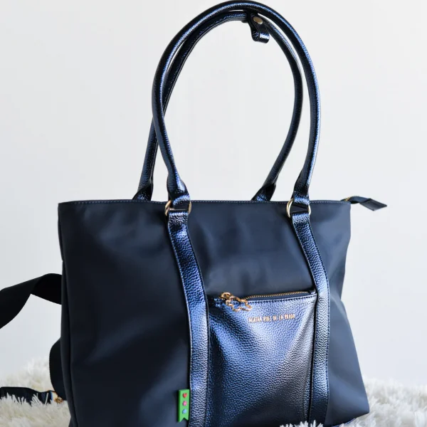 Ligero, funcional y con un toque de sofisticación. Este bolso shopper extra grande combina la resistencia y frescura del nylon con la elegancia de la piel sintética metalizada a tono, creando un accesorio versátil para el día a día. Gracias a su peso pluma y cierre superior con cremallera, es ideal para llevar todo lo que necesitas con total comodidad y seguridad. Los detalles en dorado y el icono de la nube en el tirador aportan ese sello único y exclusivo que define la colección Agatha Ruiz de la Prada. Medidas: 35*26*10