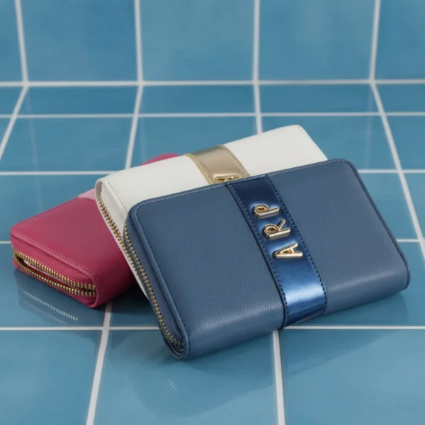 Este monedero mediano de la colección de verano de Agatha Ruiz de la Prada completa la línea con un diseño práctico y con identidad propia. Fabricado en piel sintética lisa, incorpora una línea vertical en material metalizado que aporta un toque moderno y elegante. Sobre esta franja destacan las iniciales ARP, un guiño sutil y reconocible al universo de la marca. Su tamaño mediano es ideal para quienes buscan un accesorio cómodo pero con capacidad suficiente para organizar monedas, tarjetas y billetes. Es ligero, resistente y perfecto para acompañar los bolsos de la colección, creando un conjunto coordinado y funcional. Medidas: 16*10*3