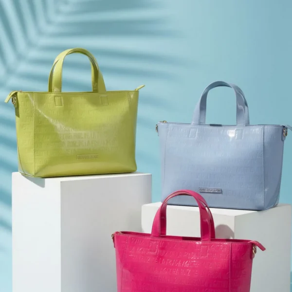 Esta shopper tipo tote de Agatha Ruiz de la Prada combina funcionalidad, estilo y color en un formato mediano ideal para el día a día. Confeccionada en charol brillante en tonos pastel, el logo de la marca grabado en toda la superficie aporta un acabado texturizado y elegante, reforzando la identidad de la firma. Su diseño incluye cierre de cremallera superior, garantizando seguridad y comodidad al llevar tus pertenencias, y ofrece espacio suficiente para todo lo imprescindible: cartera, monedero, maquillaje y accesorios. Un bolso ligero y versátil que se adapta a cualquier ocasión, desde recados y trabajo hasta salidas informales. Un bolso práctico, moderno y con personalidad, perfecto para combinar con los accesorios de la colección pastel y aportar un toque de color y estilo a cualquier look.e Medidas: 32*24*10