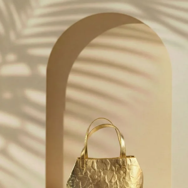 Este bolso tote de Agatha Ruiz de la Prada está diseñado en piel sintética metalizada, con un acabado elegante y luminoso que aporta un toque sofisticado a cualquier look. El material incorpora los iconos de la marca grabados con volumen, creando un efecto en relieve que añade textura y personalidad al diseño. El bolso incluye un neceser interior con cremallera, ideal para organizar y proteger los objetos más pequeños. Además, cuenta con un cierre interior, que aporta un extra de seguridad sin perder comodidad. Su formato tote es amplio y práctico, perfecto para el uso diario, trabajo o planes en los que necesitas más capacidad. Un modelo funcional y elegante que combina diseño, organización y la identidad inconfundible de Agatha Ruiz de la Prada. Medidas: 27*28*13