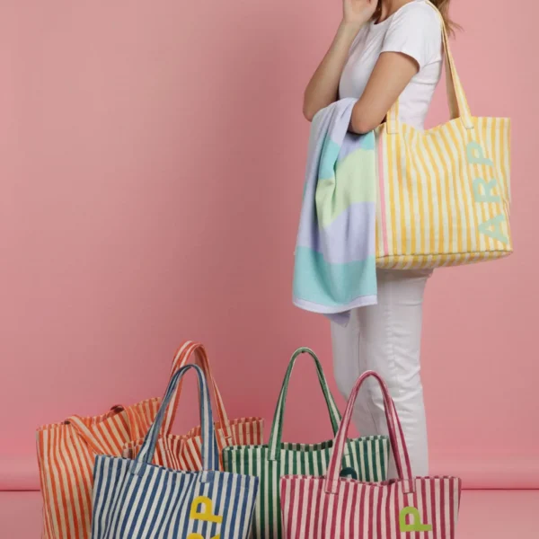 Esta tote bag de Agatha Ruiz de la Prada está diseñada para quienes buscan un bolso amplio, resistente y con estilo para el verano. Confeccionada en lona gruesa de alta calidad, combina líneas de color y el logo de la marca en goma a contraste con las iniciales ARP, aportando un acabado moderno y alegre que refleja la identidad de la firma. Su formato extra amplio la convierte en la opción perfecta para llevar todo lo imprescindible en la playa: toalla, crema solar, libro, gafas de sol y más. Gracias a sus asas largas, resulta cómoda de llevar al hombro o en la mano, adaptándose a cualquier plan de verano. Un bolso ligero, duradero y muy funcional, ideal para disfrutar del sol y la playa sin renunciar al diseño y color característicos de Agatha Ruiz de la Prada. Medidas: 43*37*14